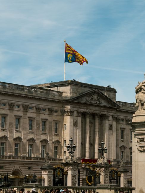 A close-up view of the upper section of a historic stone building, featuring classical architectural elements such as ornate columns with Corinthian capitals supporting a triangular pediment decorated
